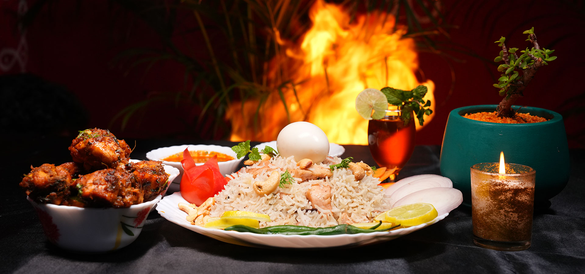 Chittibabu Kodi Pulav Andhra chicken rice served with boiled egg, spicy chicken fry, chutney and drink in a restaurant ambience with fire backgr