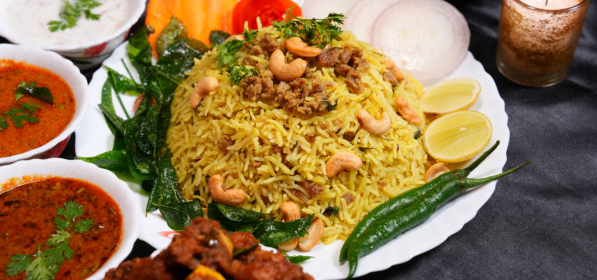 Chittibabu Kodi Pulav Andhra chicken rice served with boiled egg, spicy chicken fry, chutney and drink in a restaurant ambience with fire backgr